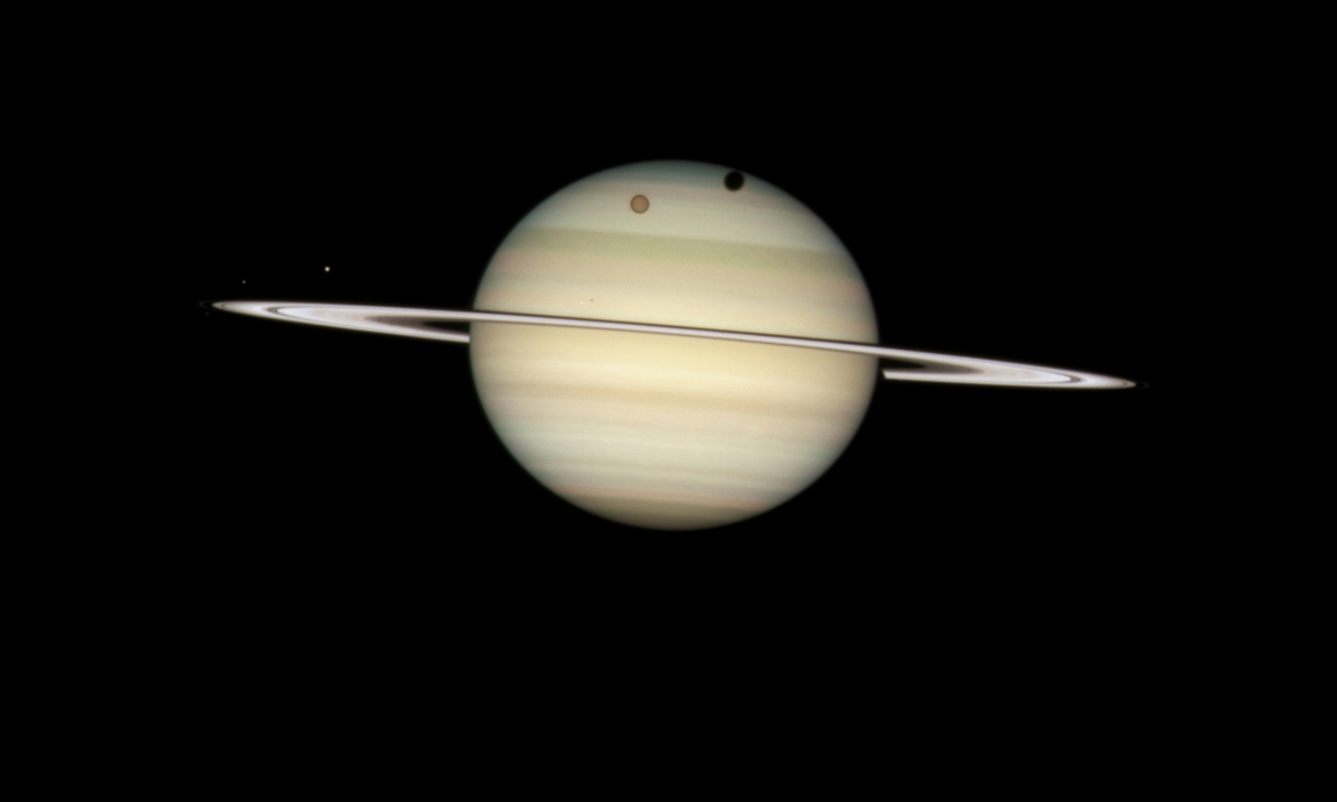 Hubble registra um fenômeno raro, o trânsito de uma lua em Saturno, conseguindo também registrar a sombra da lua Titã passando pela região polar norte do planeta. E na parte equatorial o trânsito da lua Mimas.