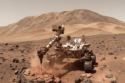 O rover Curiosity da NASA perfura uma rocha na Cratera Gale, desvendando bilhões de anos da história geológica de Marte através de suas camadas estratificadas.
