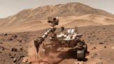 O rover Curiosity da NASA perfura uma rocha na Cratera Gale, desvendando bilhões de anos da história geológica de Marte através de suas camadas estratificadas.